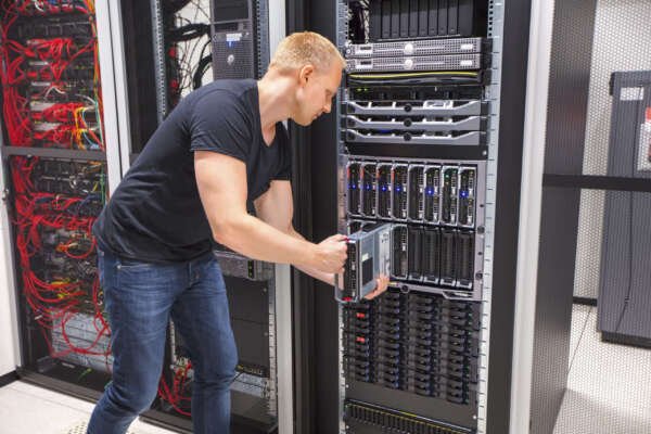 Mid adult male computer engineer installing blade server in chassis at datacenter